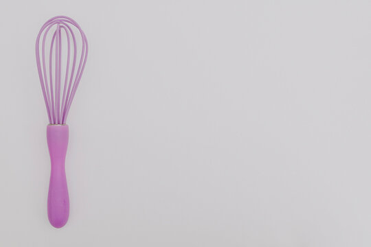 Purple whisk for the kitchen on a white background