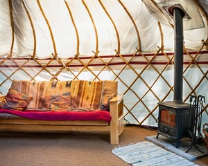 Interior of a glamping tent with a couch and fireplace heater