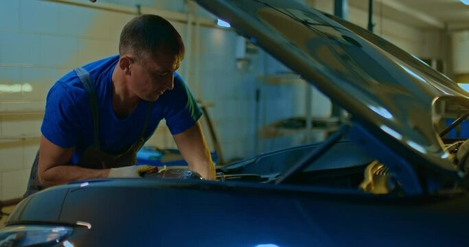 Auto mechanic checks the car engine under the hood. Car service.
