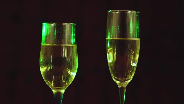 Two glasses of champagne on a dark background. Congratulation, postcard. Background, insert captions, inscription, congratulations. Video footage,intro copy space. UHD 4K.