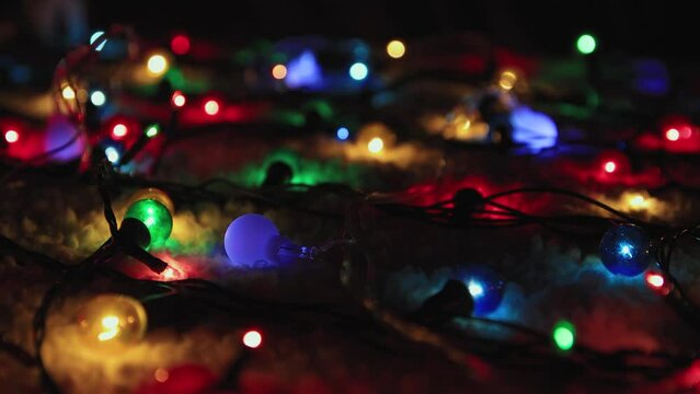 Sparkling Christmas garland on a black background. Place to copy. New Year multi-colored lights in defocus. Beautiful holiday card, video for intro, text, intro. UHD 4K.