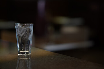 A glass of water with ice on a dark environment, low key light photography
