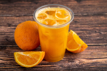 Freshly squeezed orange juice with ice cubes on wooden table