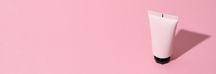 Tube of cosmetic on pink background, space for text