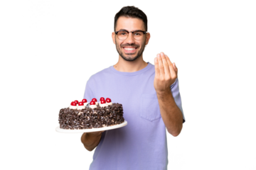 Young caucasian man holding birthday cake isolated on green chrome background inviting to come with hand. Happy that you came