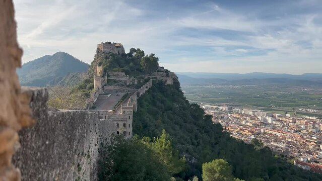 Medieval castle view from the wall through the chains in clear weather with white clouds. Located in the city of Xativa near Valencia, Spain
