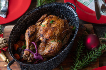 Christmas roast chicken with vegetables and sauce in a old fashioned roaster on laid wooden table