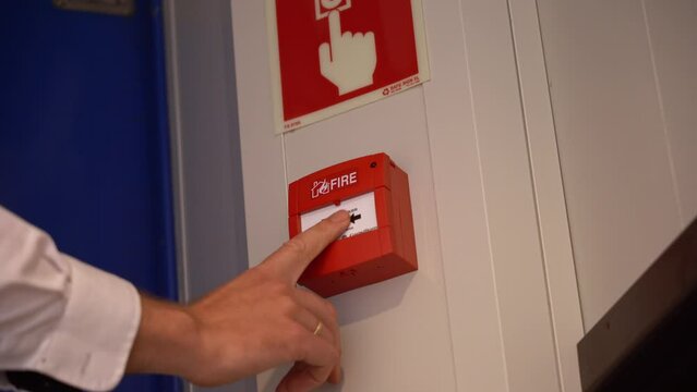Ships crew showing how to release fire alarm onboard ship - Low angle closeup of hand and alarm release button - Low angle static