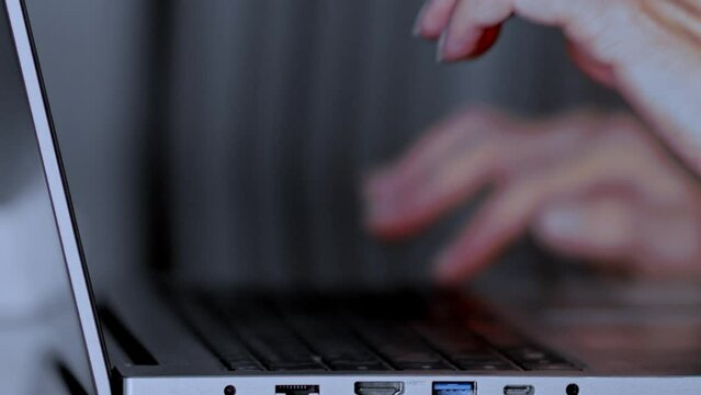 Close up of a woman opening her laptop and typing on it in slow motion