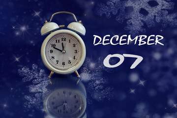 Calendar for December 7: white alarm clock on a blue background with bokeh, reflection from objects, name of the month december, numbers 07