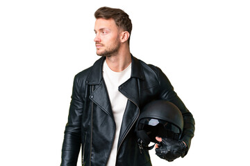 Young caucasian man with a motorcycle helmet over isolated chroma key background looking to the side