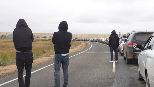Back view of unrecognizable people standing in long queue of cars waiting in large traffic jam at customs border crossing between Kazakhstan and Russia, after announcement of partial mobilization.
