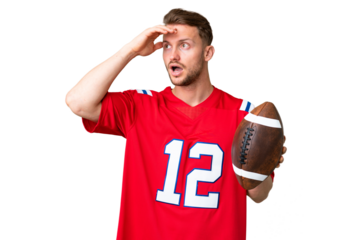 Young caucasian man playing rugby over isolated chroma key background doing surprise gesture while looking to the side