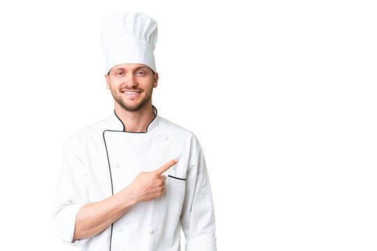 Young caucasian chef over isolated chroma key background pointing to the side to present a product