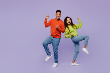 Full body young couple two friends family man woman of African American ethnicity wear casual clothes together doing winner gesture celebrate clenching fists isolated on plain light purple background.