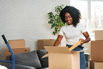 Happy african young woman with cardboard box moving to a new place