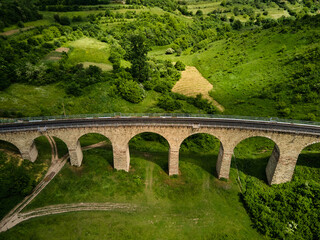 Fototapeta na wymiar Aerial view of an old railway viaduct, Austro-Hungarian railway bridge in the village of Plebanivka in the Ternopil region of Ukraine, Travel sight points in Ukraine