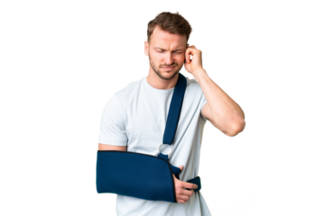 Young caucasian man with broken arm and wearing a sling over isolated chroma key background frustrated and covering ears