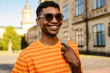 Young black man wearing piercing and sunglasses walking in park