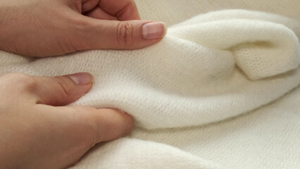 female's hand on the fabric of white plush cloth with soft nap. Clothing industry concept, slow motion. woman checking the quality of clothes, enjoys the soft pleasant texture of the fabric