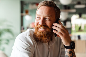 White ginger man talking on cellphone indoors