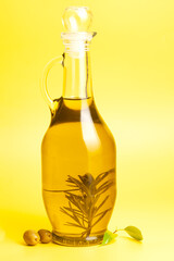 Jug with olive oil, green olives on yellow background.