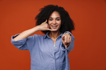 Young woman with curly hair gesturing call sign at camera