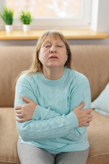 Indoor portrait of happy elderly woman hugging herself, giving support, showing self-respect and...