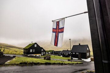 Faroe islands flag with houses in village under overcast sky