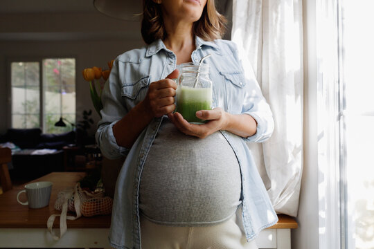 Pregnant woman standing by window at home