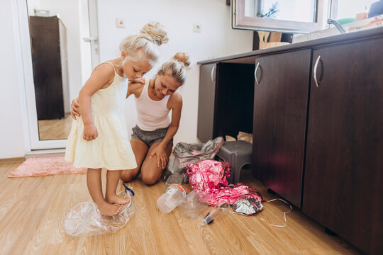 Mother and daughter collecting plastic trash in the kitchen