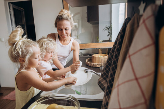 Woman with daughters washing dishes in the kitchen