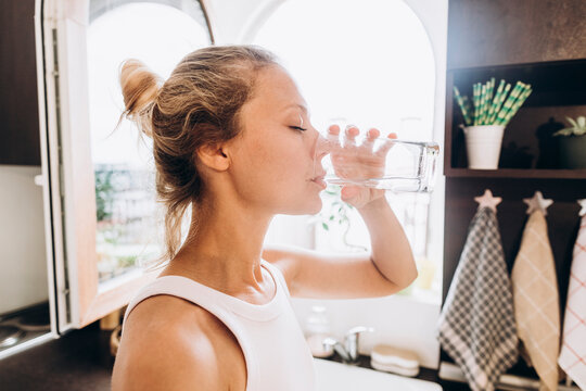 Woman drinking water from a glass in the kitchen