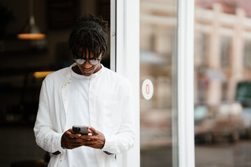Young african man using mobile phone while standing outdoors
