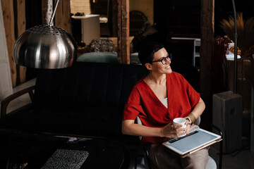 European woman drinking coffee and working with tablet computer