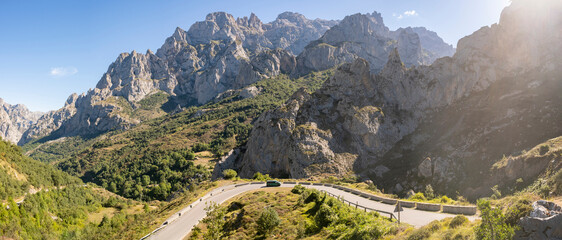 Spain, Castile and Leon, Posada de Valdeon, Panoramic view of Picos de Europa range in summer with asphalt road in foreground