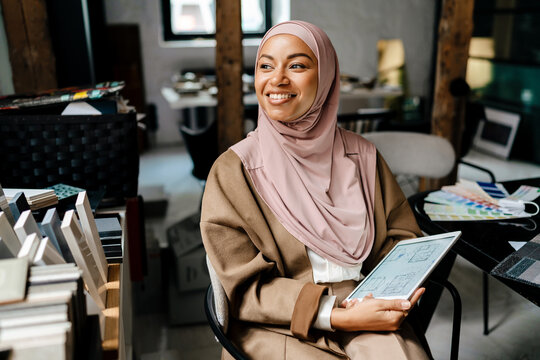 Female muslim designer working on tablet computer at workshop