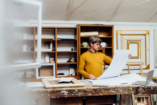 Craftsman looking at blueprint in studio