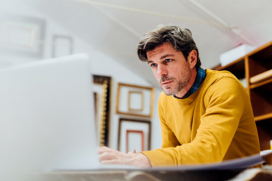 Focused craftsman using laptop at workshop