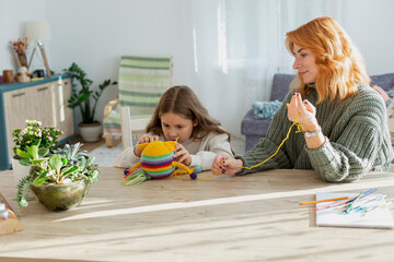 Mother and daughter sitting and knitting a woollen toy