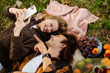 Top view of loving couple using mobile phone while resting on grass in park