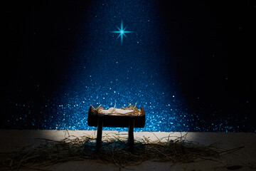 Nativity of Jesus, empty manger at night with bright lights.