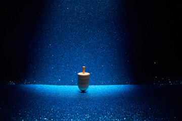 Hanukkah traditional dreidel with letters Gimel and Nun on shining blue background