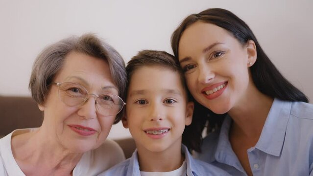 Happy family portrait, grandmother, mother and son hugging, smiling on camera