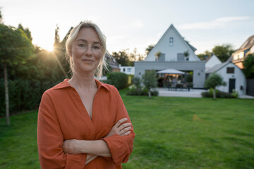 Smiling woman with arms crossed in back yard
