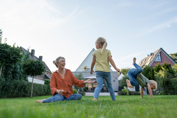 Cheerful mother with son and daughter enjoying in garden