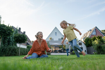 Happy woman with daughter and son enjoying in back yard