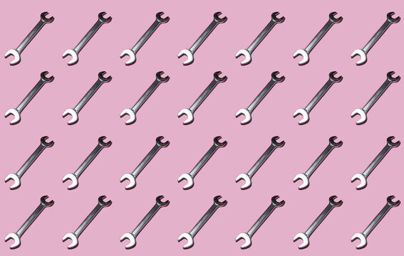 Pattern of rows of wrenches flat laid against pink background