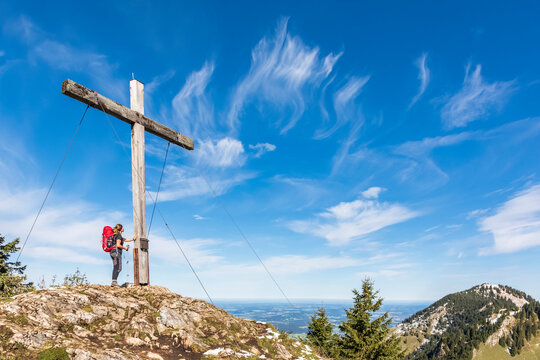 Germany, Bavaria, Female hiker standing in front of summit cross of Karkopf mountain