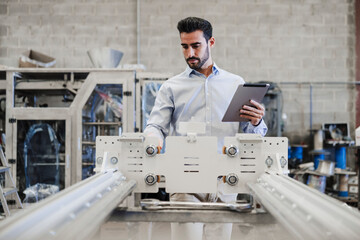 Engineer with tablet PC operating machine at industry